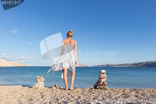 Image of Happy carefree woman enjoying late afternoon walk on white pabbled beach on Pag island, Croatia