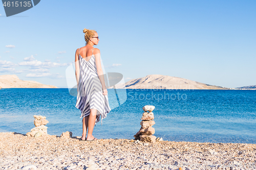 Image of Happy carefree woman enjoying late afternoon walk on white pabbled beach on Pag island, Croatia