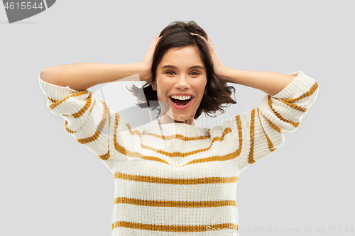 Image of happy woman in pullover holding to her head