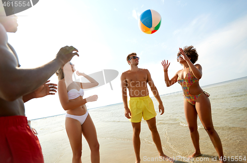 Image of happy friends playing ball on summer beach