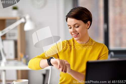 Image of happy businesswoman using smart watch at office