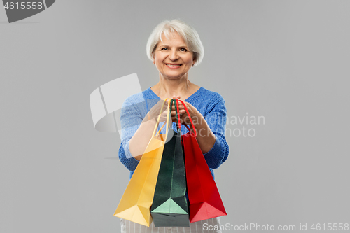 Image of senior woman with shopping bags over grey