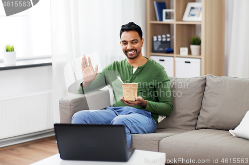 Image of man having video call on laptop and eating at home