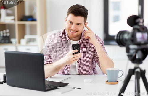 Image of male blogger with earphones videoblogging at home