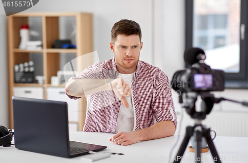 Image of male blogger with camera videoblogging at home