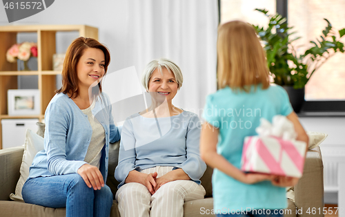 Image of grandmother, mother and daughter with gift box