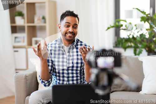 Image of male blogger with camera videoblogging at home