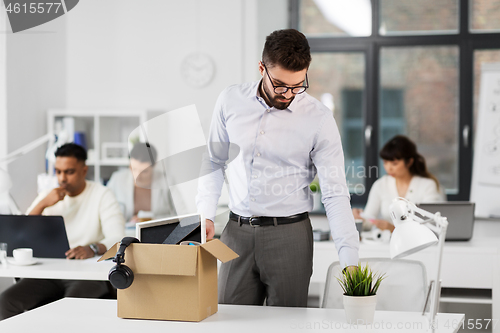 Image of sad fired male office worker with personal stuff