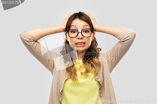 Image of asian female student in glasses holding to head