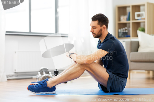 Image of man with fitness tracker exercising at home