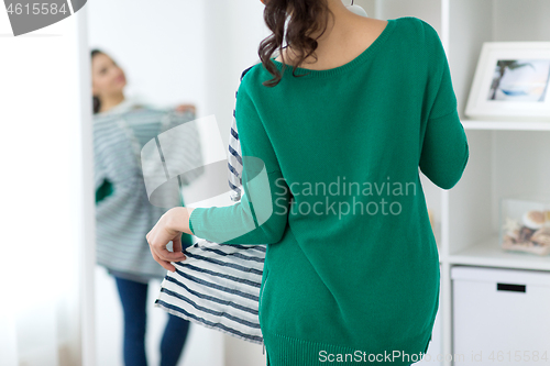 Image of close up of woman choosing clothes at home mirror