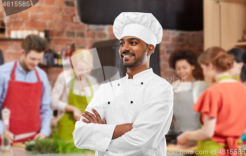 Image of happy male indian chef in toque at cooking class