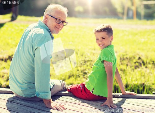 Image of grandfather and grandson sitting on river berth