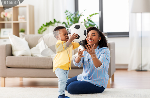 Image of mother and baby playing with soccer ball at home