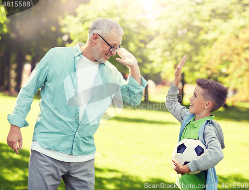 Image of old man and boy with soccer ball making high five