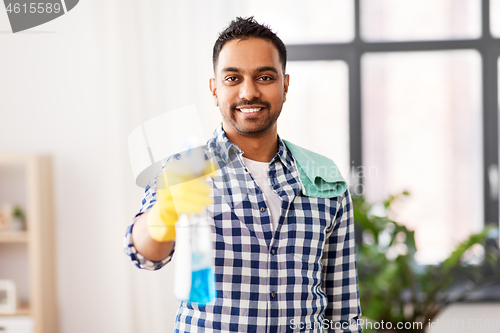 Image of smiling indian man with detergent cleaning at home