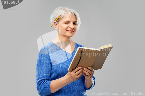 Image of senior woman with pencil and diary or notebook