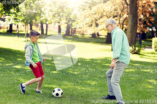 Image of old man and boy playing football at summer park
