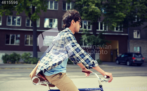 Image of young hipster man with bag riding fixed gear bike