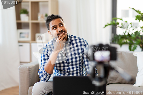 Image of male blogger with camera videoblogging at home