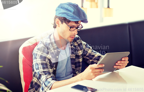 Image of man with tablet pc sitting at cafe table