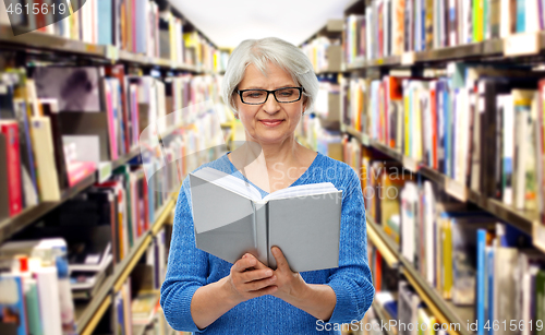 Image of senior woman in glasses reading book at library