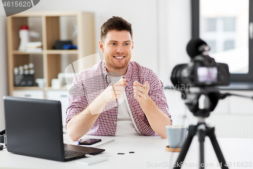 Image of male blogger with camera videoblogging at home