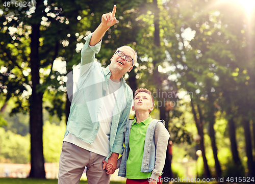 Image of grandfather and boy pointing up at summer park