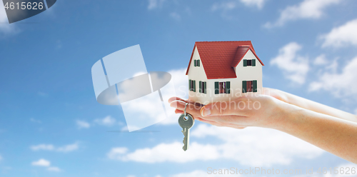 Image of close up of hands holding house model and keys