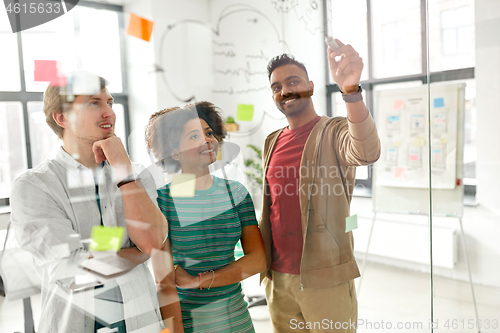 Image of happy creative team at office glass board