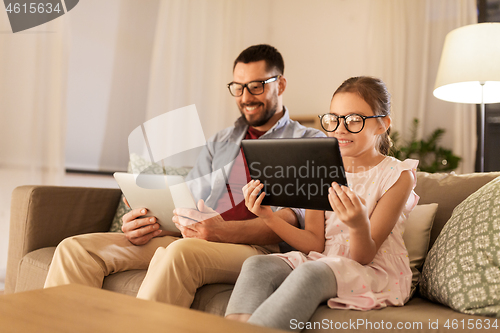 Image of father and daughter with tablet computers at home