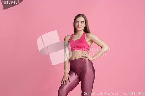 Image of Beautiful young female athlete practicing on pink studio background, monochrome portrait