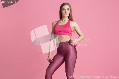 Image of Beautiful young female athlete practicing on pink studio background, monochrome portrait