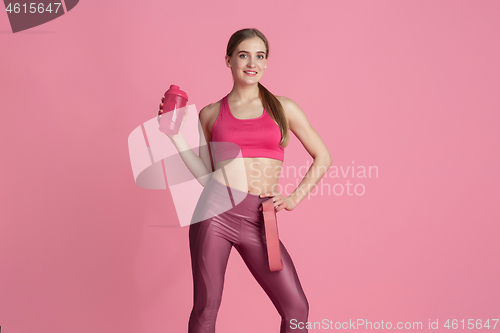 Image of Beautiful young female athlete practicing on pink studio background, monochrome portrait