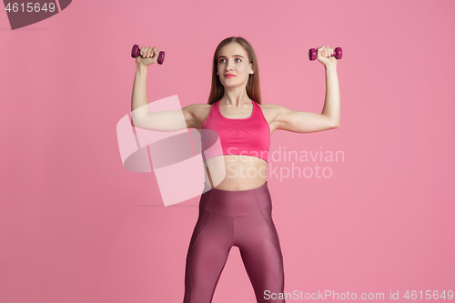 Image of Beautiful young female athlete practicing on pink studio background, monochrome portrait