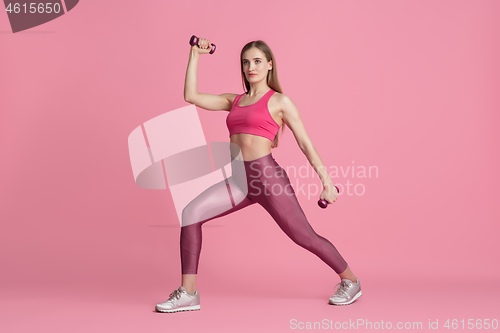 Image of Beautiful young female athlete practicing on pink studio background, monochrome portrait