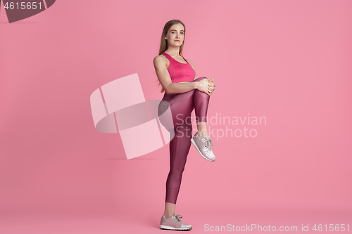 Image of Beautiful young female athlete practicing on pink studio background, monochrome portrait