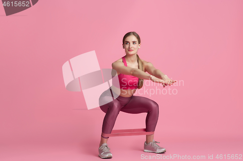 Image of Beautiful young female athlete practicing on pink studio background, monochrome portrait