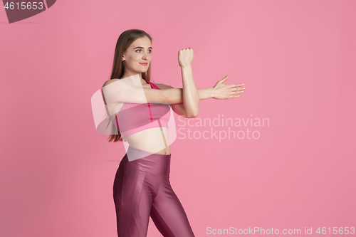 Image of Beautiful young female athlete practicing on pink studio background, monochrome portrait