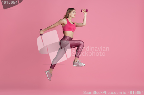 Image of Beautiful young female athlete practicing on pink studio background, monochrome portrait