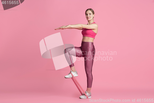 Image of Beautiful young female athlete practicing on pink studio background, monochrome portrait