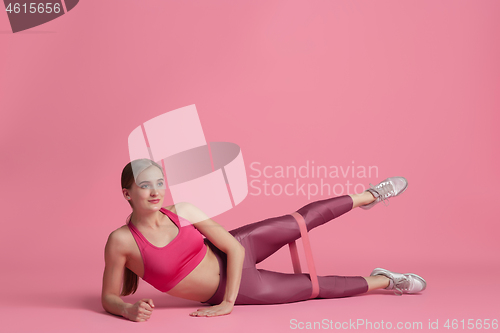 Image of Beautiful young female athlete practicing on pink studio background, monochrome portrait