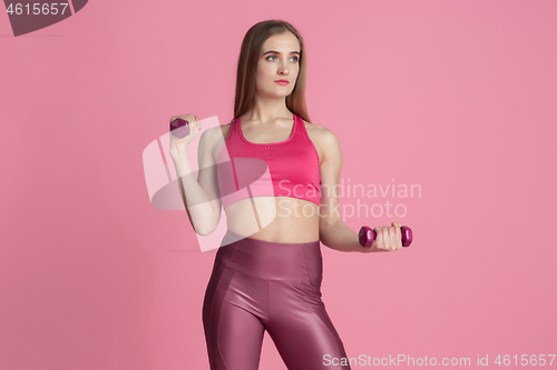 Image of Beautiful young female athlete practicing on pink studio background, monochrome portrait