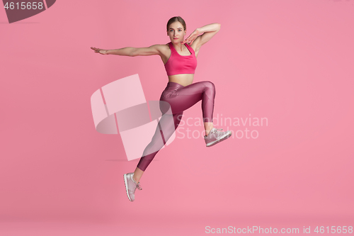 Image of Beautiful young female athlete practicing on pink studio background, monochrome portrait