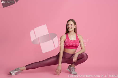 Image of Beautiful young female athlete practicing on pink studio background, monochrome portrait