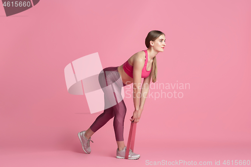 Image of Beautiful young female athlete practicing on pink studio background, monochrome portrait