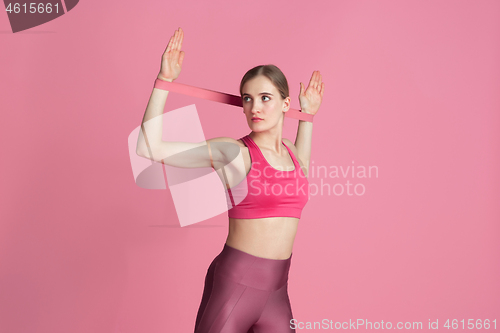 Image of Beautiful young female athlete practicing on pink studio background, monochrome portrait