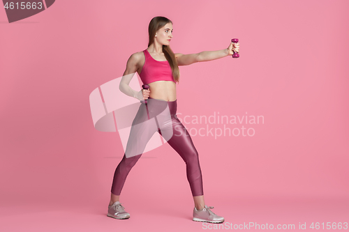 Image of Beautiful young female athlete practicing on pink studio background, monochrome portrait