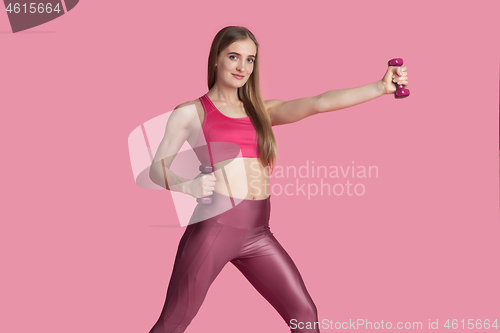 Image of Beautiful young female athlete practicing on pink studio background, monochrome portrait