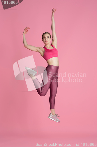 Image of Beautiful young female athlete practicing on pink studio background, monochrome portrait